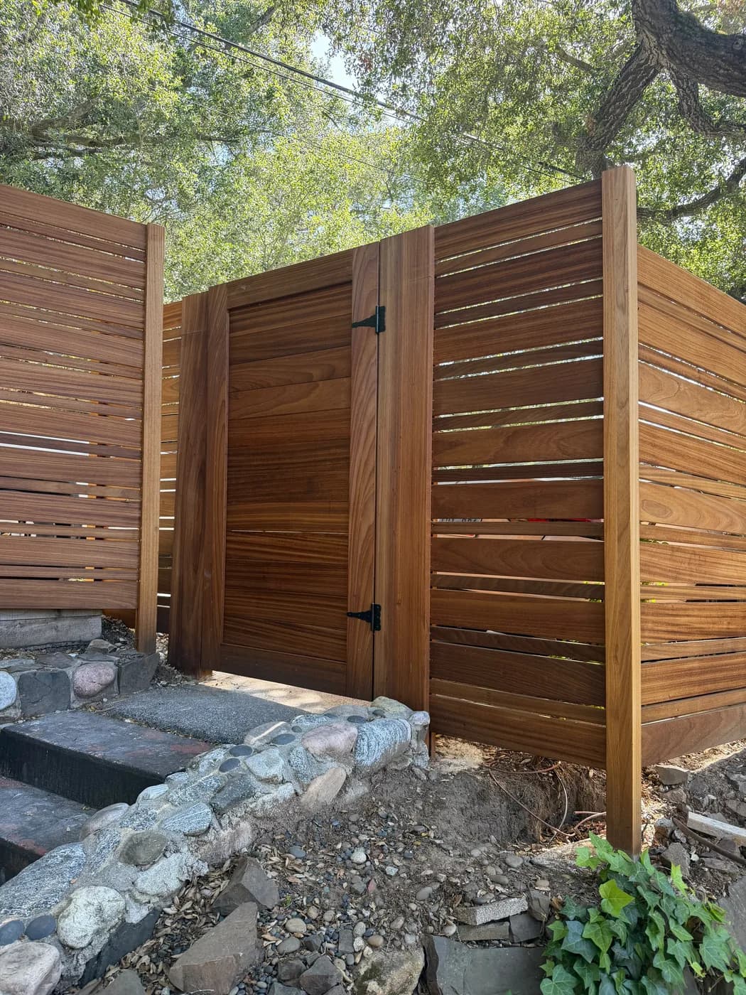 Wood privacy fence corner detail along a paved driveway