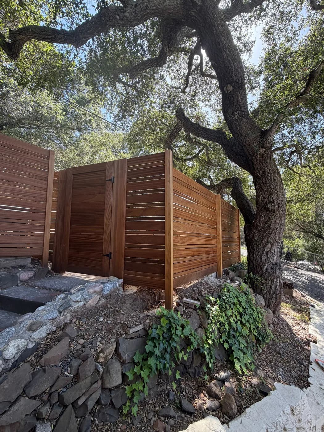Wood privacy fence bordering a paver driveway with turf inlay