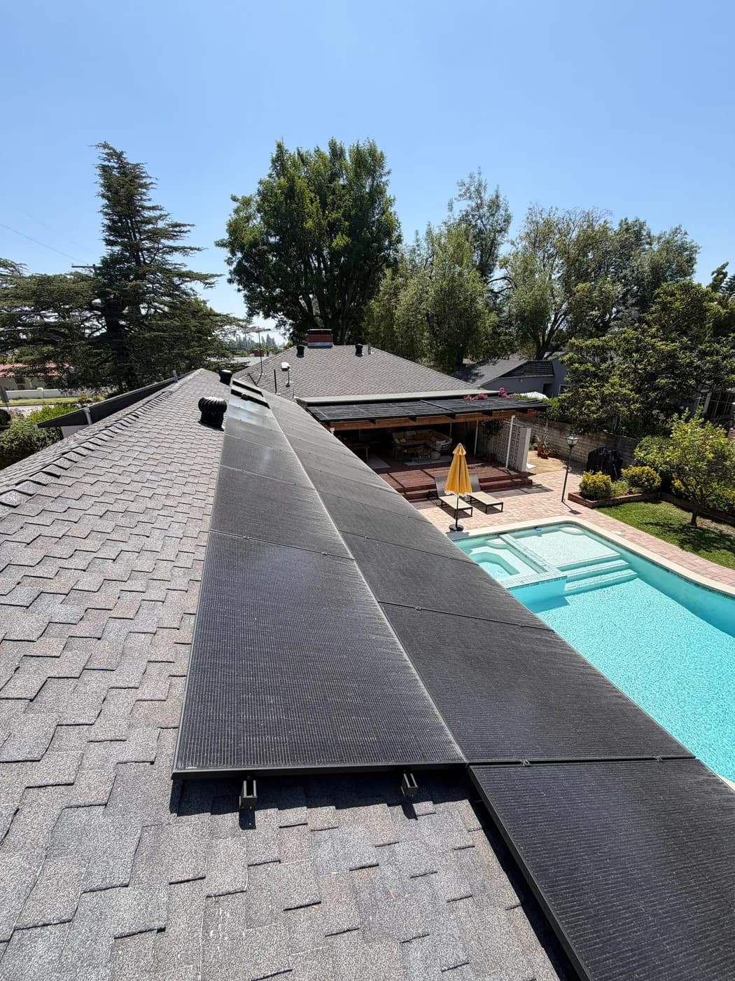 Solar panel roof installation overlooking a backyard pool and covered patio