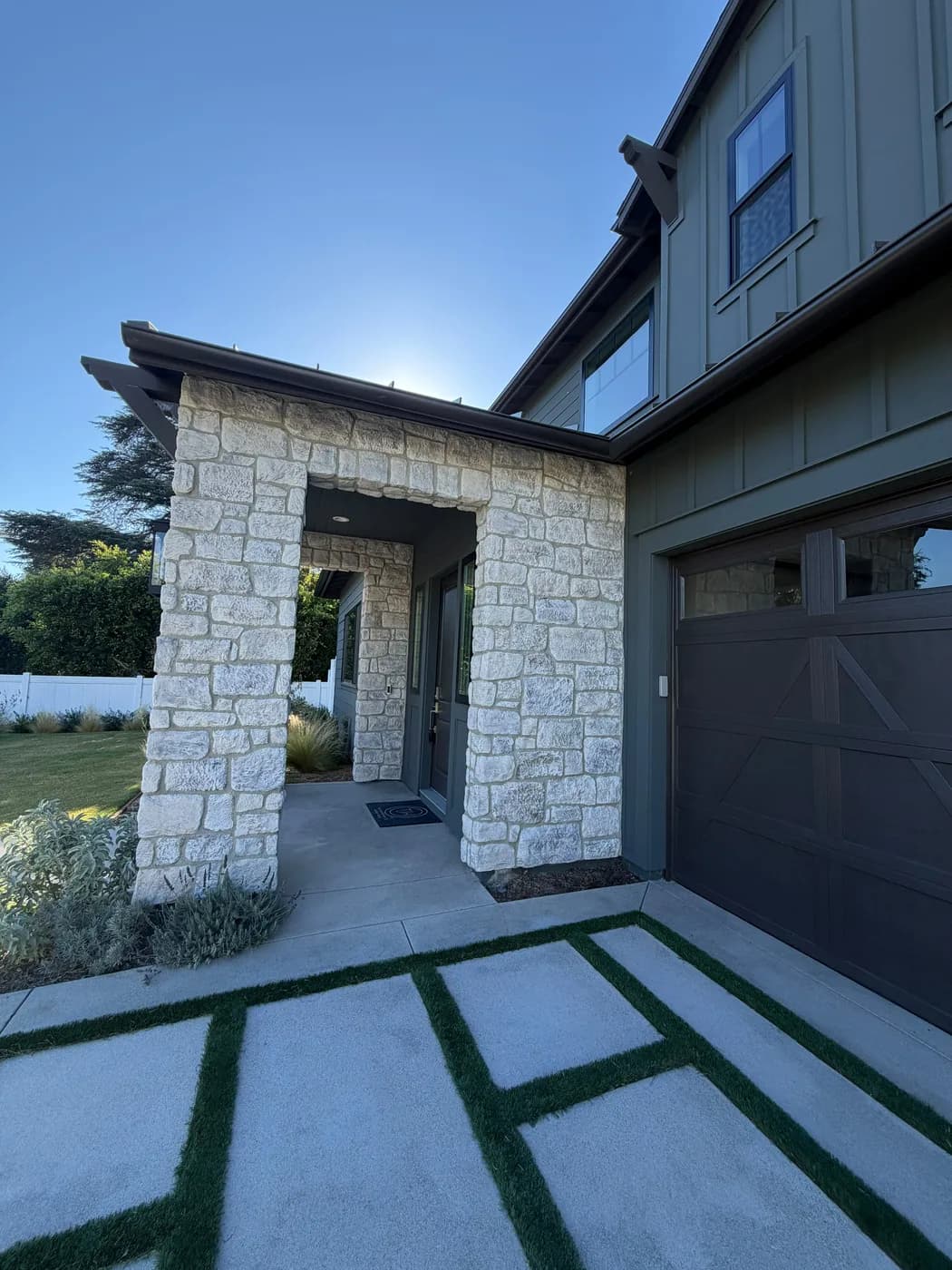 Stone archway entrance with a paver walkway and turf-inlay driveway