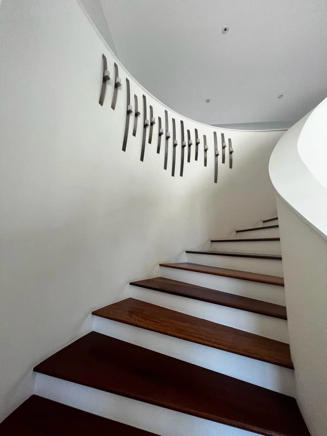 Curved staircase with wood treads by Top Tech Builders