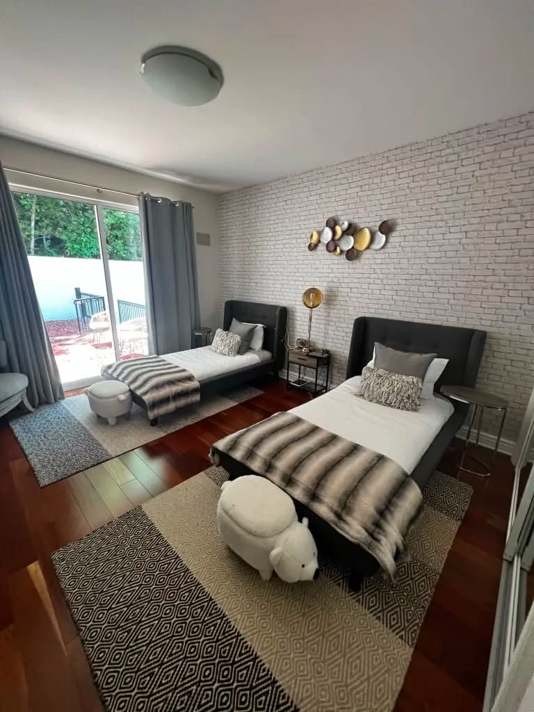 Twin bedroom with brick accent wall by Top Tech Builders