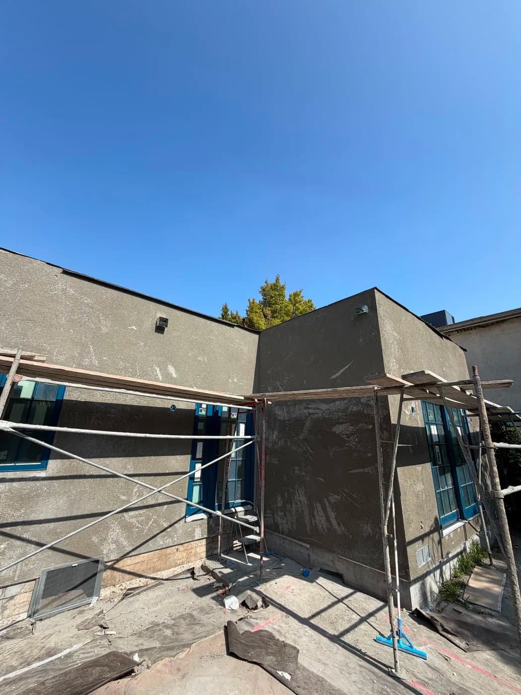 Stucco exterior renovation with scaffolding by Top Tech Builders