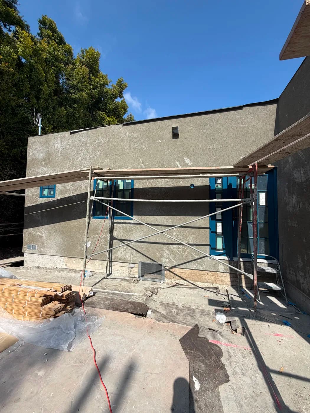 Exterior stucco wall under construction with scaffolding by Top Tech Builders