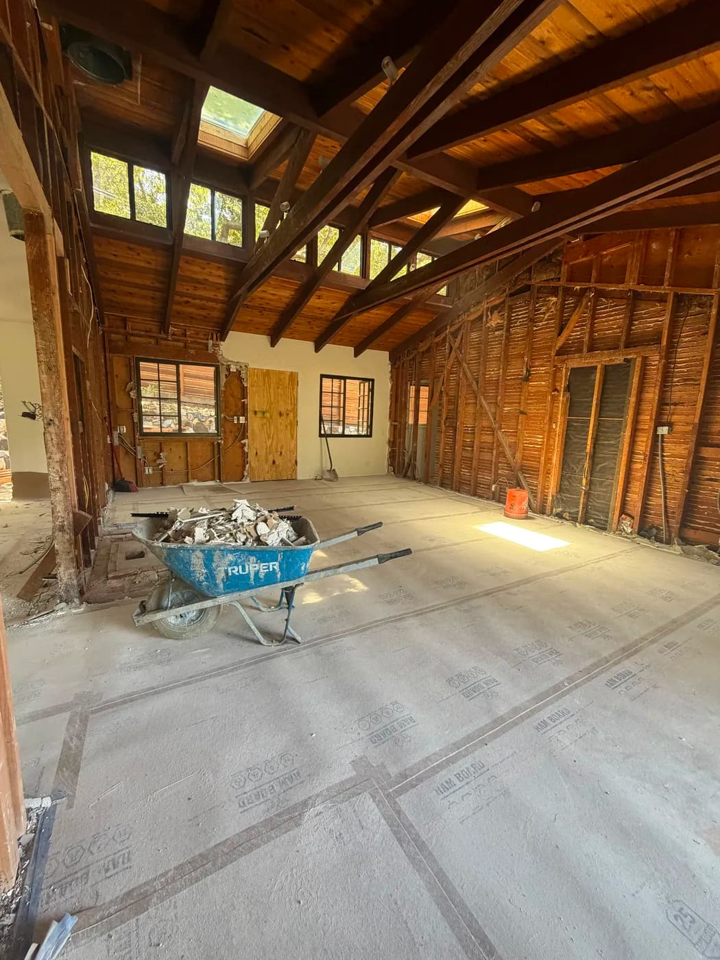 Gutted interior room with exposed wood beam ceiling by Top Tech Builders