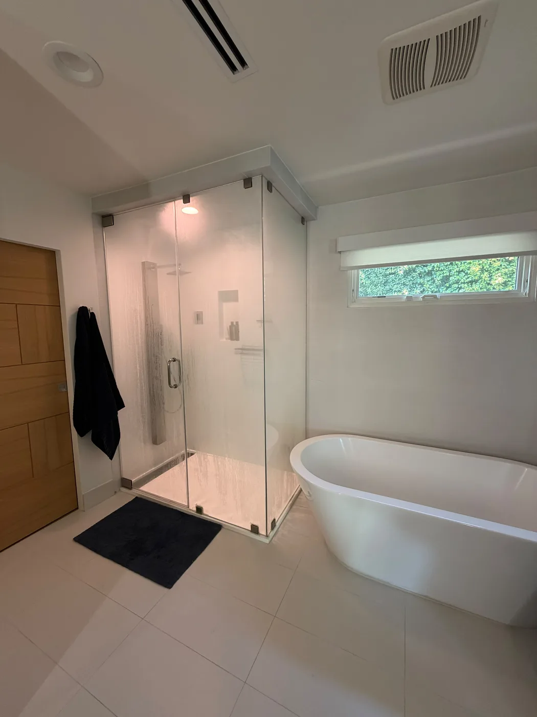 Modern bathroom remodel with glass shower and freestanding tub by Top Tech Builders