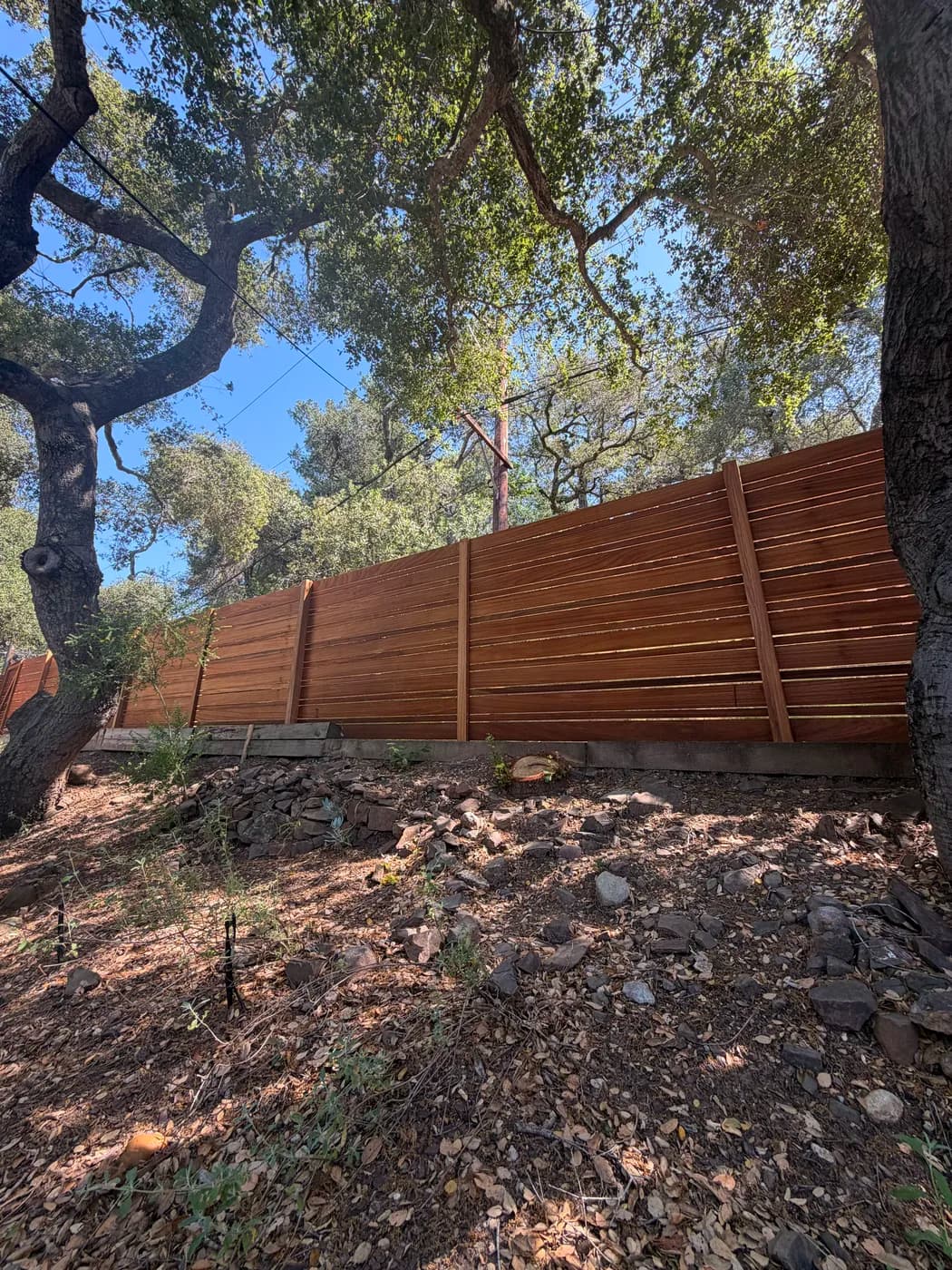 Wood privacy fence on wooded hillside by Top Tech Builders