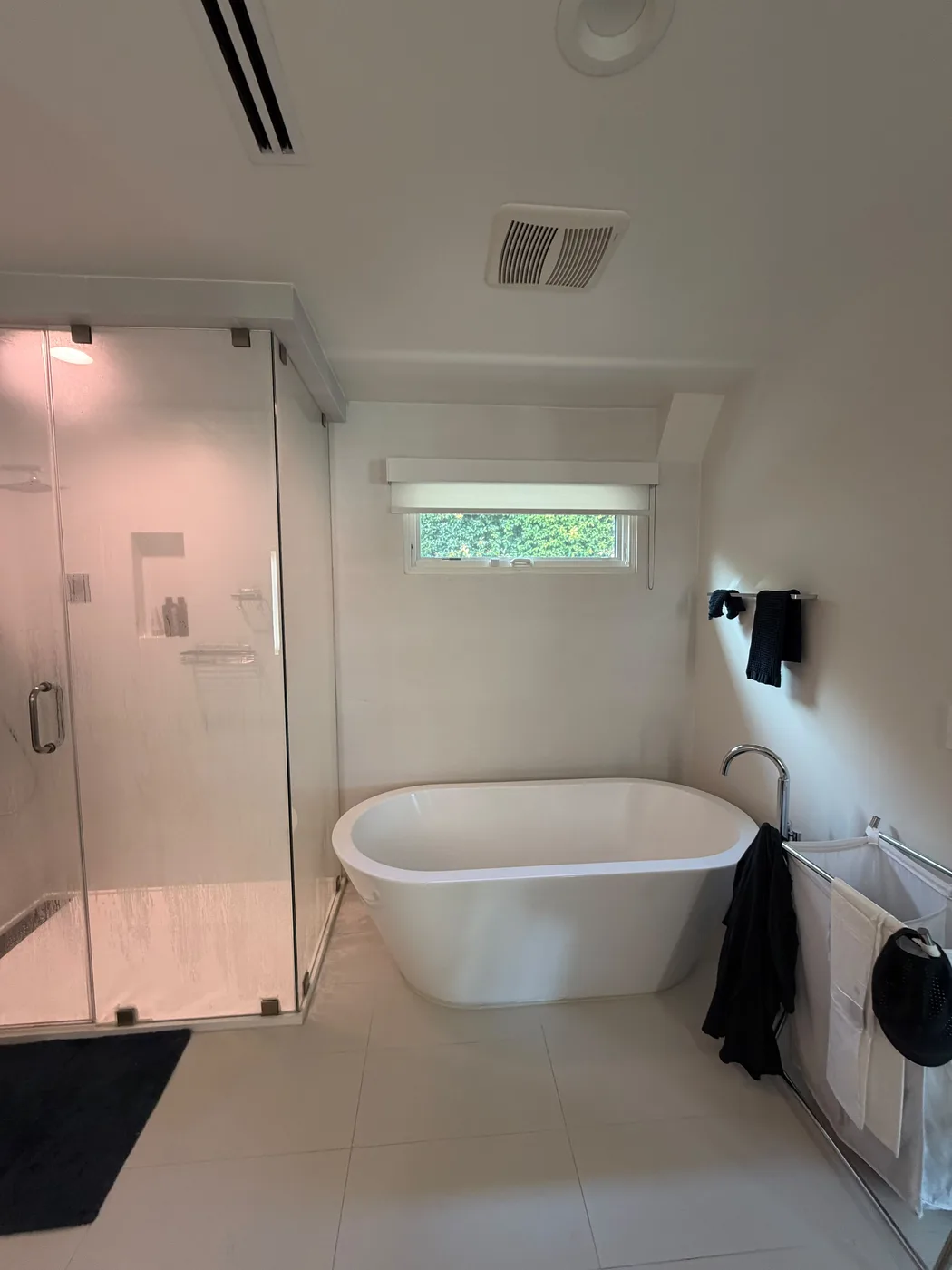 Freestanding soaking tub below window by Top Tech Builders