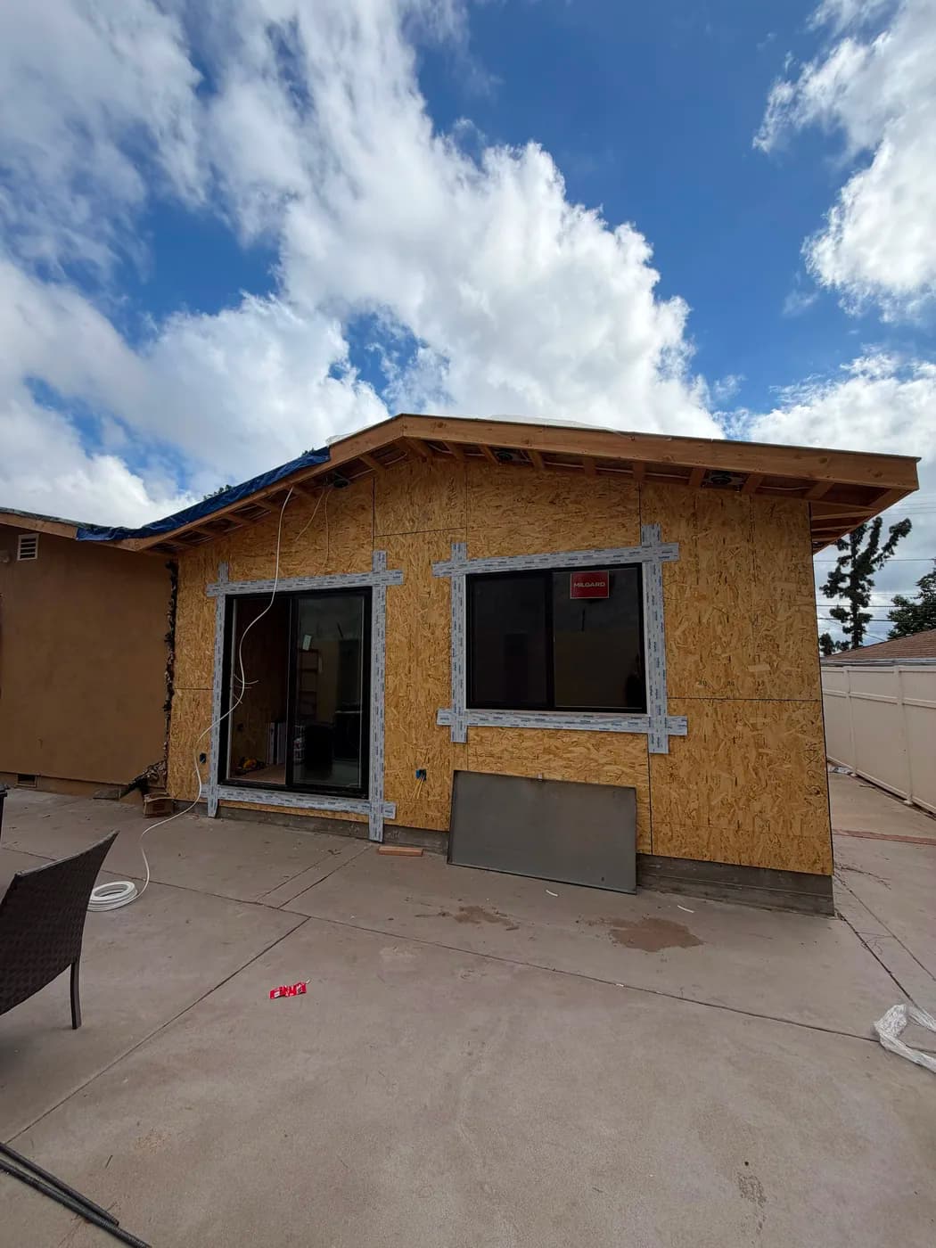 New room addition exterior with windows and sliding door by Top Tech Builders