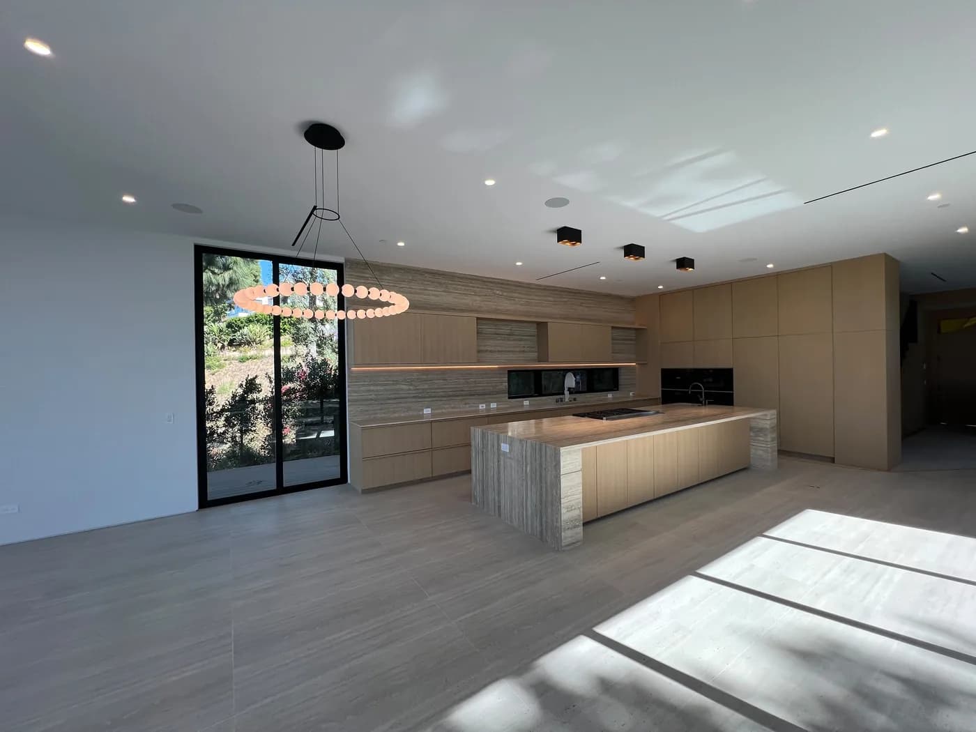Open-concept kitchen with large island, ring pendant light, and large-format tile flooring
