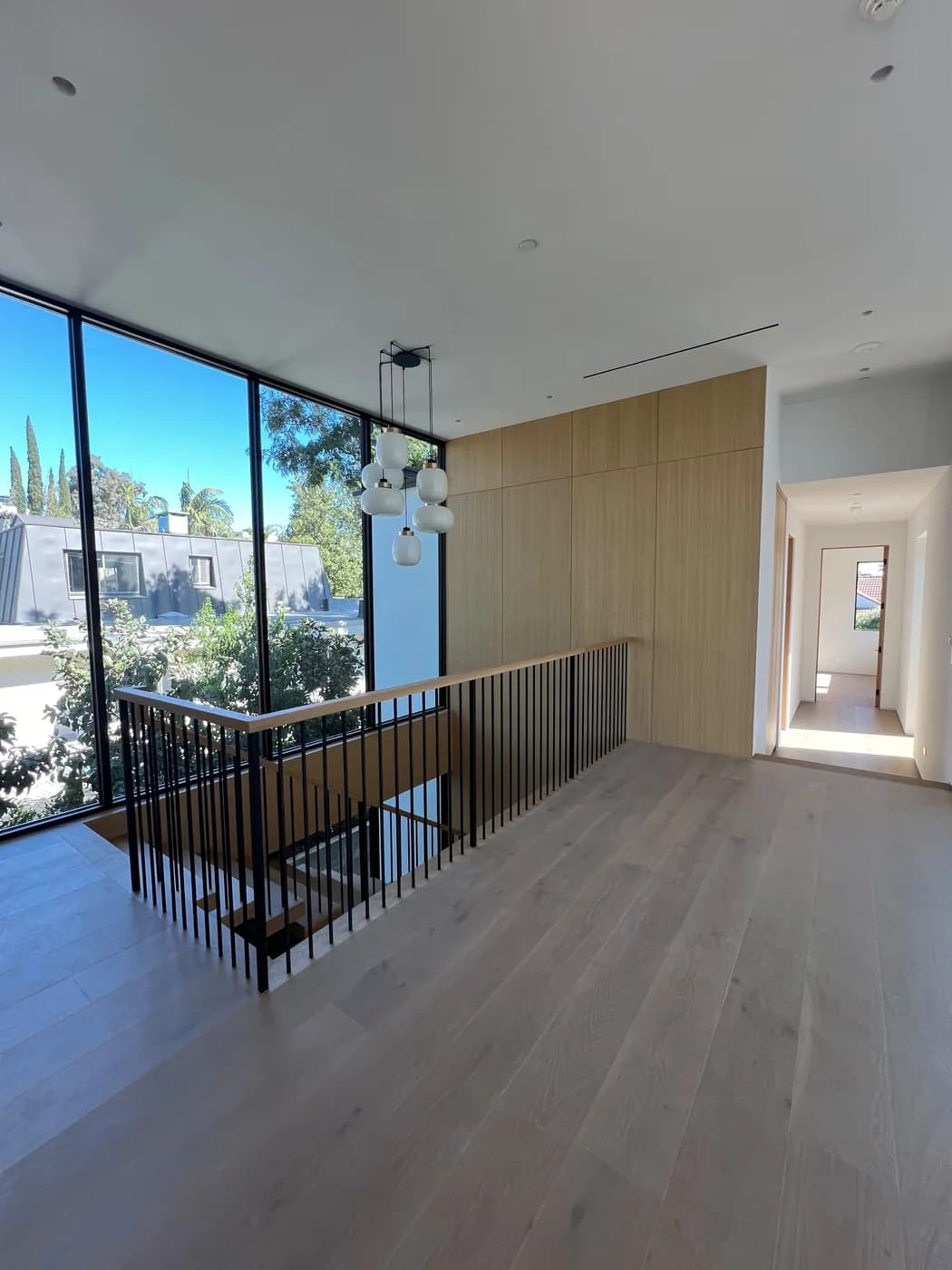 Second-floor stairwell landing with floor-to-ceiling glass and oak wood paneling