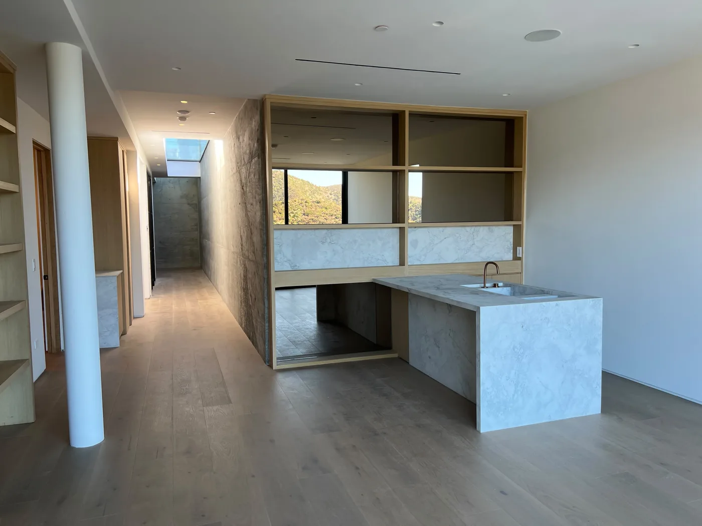 Wet bar area opening onto a hallway with a concrete accent wall